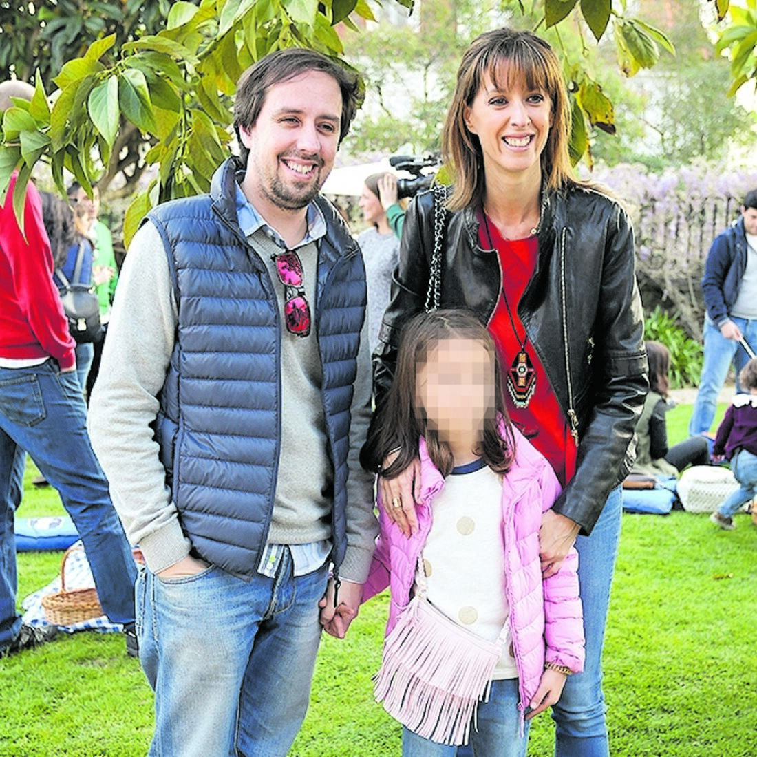 Família reunida num evento ao ar livre, com pais e filha em primeiro plano