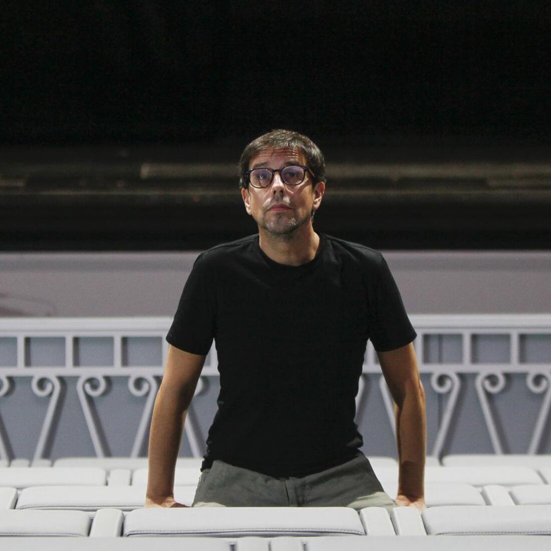 Homem de óculos pousa para foto num teatro