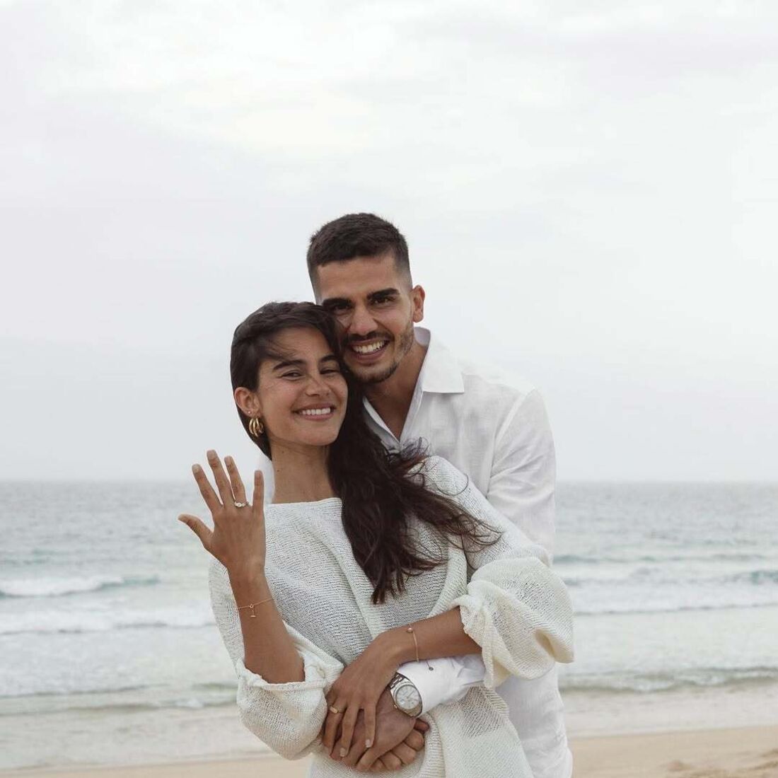 Casal celebra noivado na praia com sorrisos e alianças