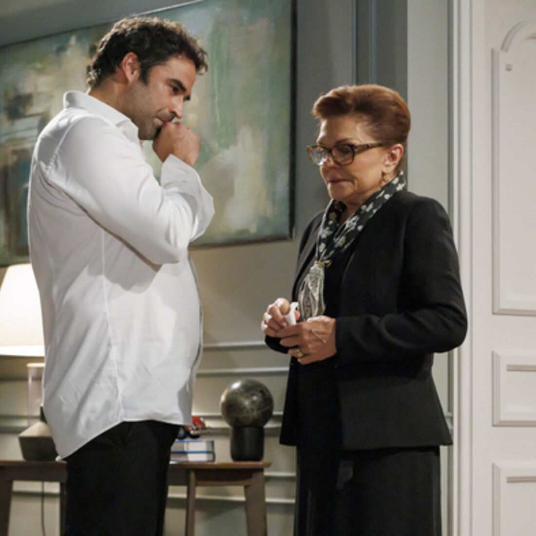 Um homem parece preocupado enquanto uma mulher mais velha o observa