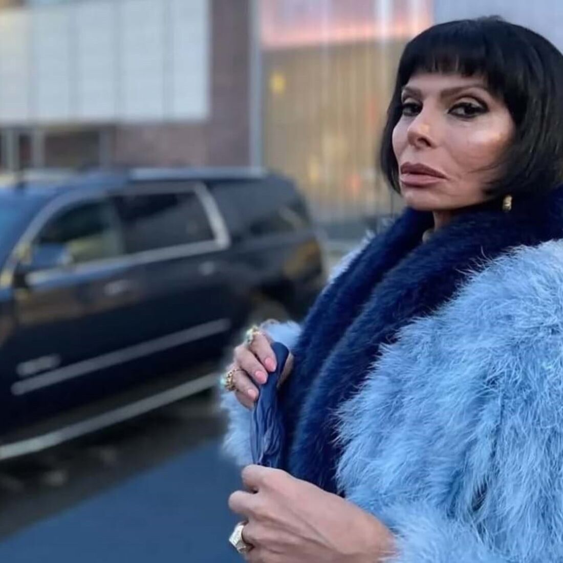 Mulher posa com casaco de pelo azul e preto na rua