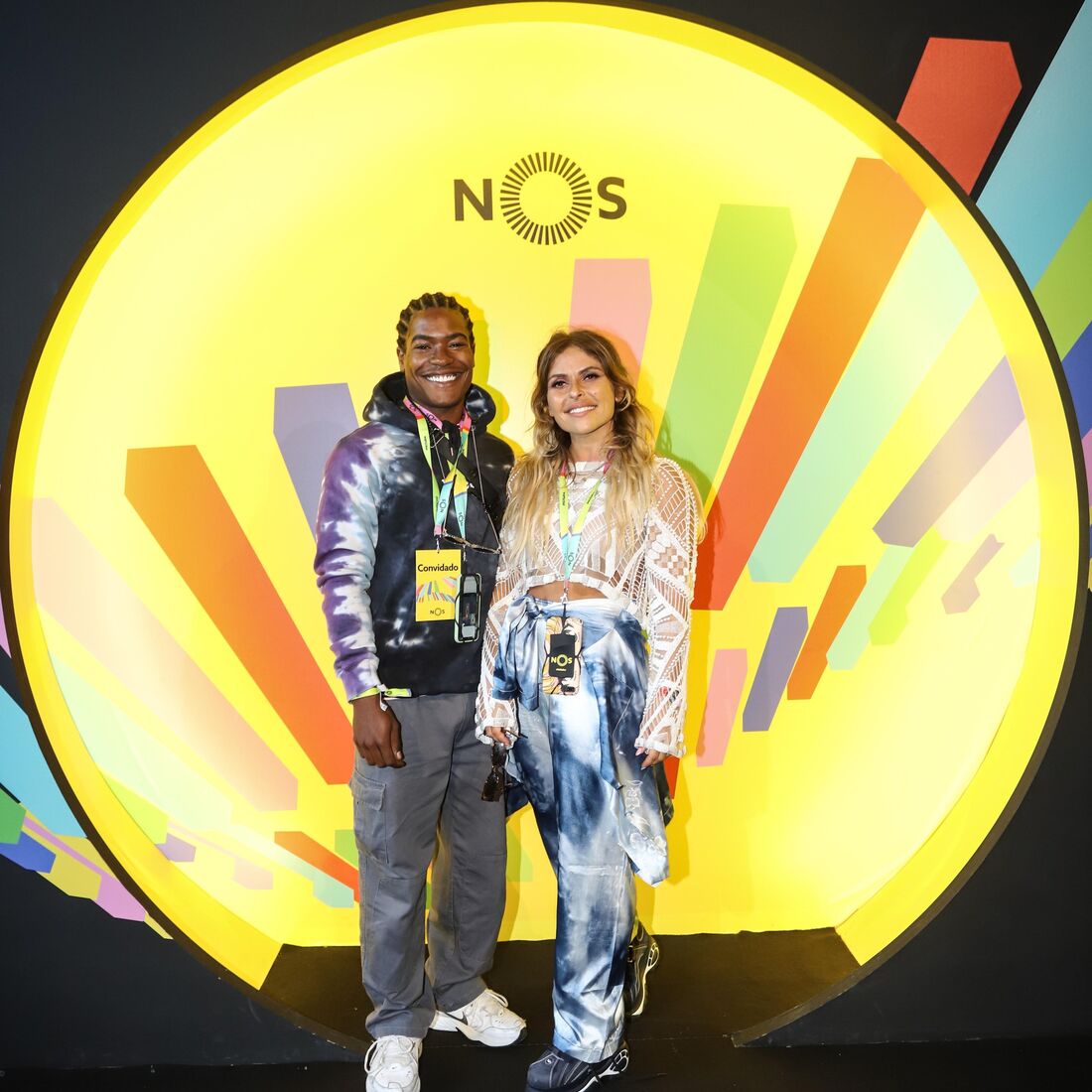 Dois convidados posam para foto com o logótipo da NOS