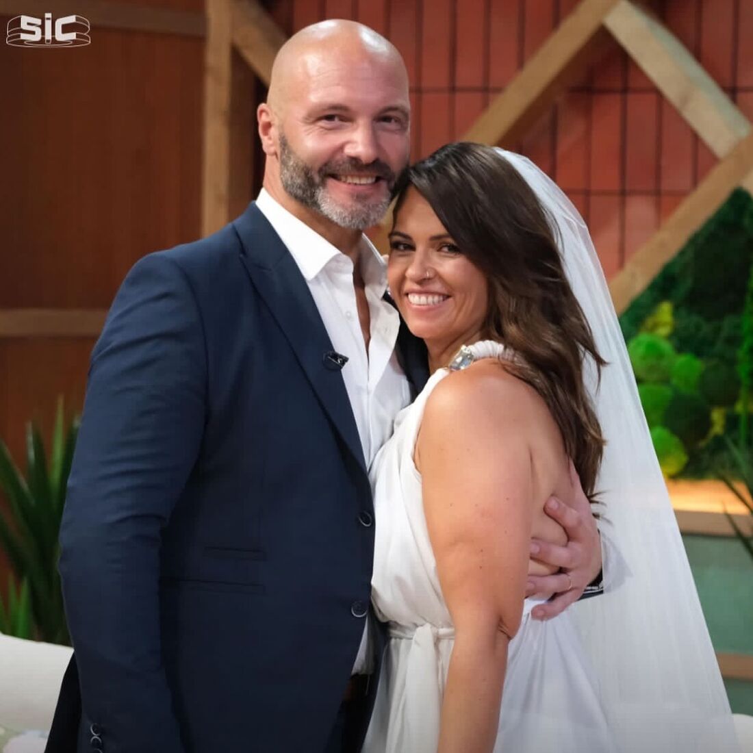 Um homem e uma mulher sorriem, num dia de casamento.
