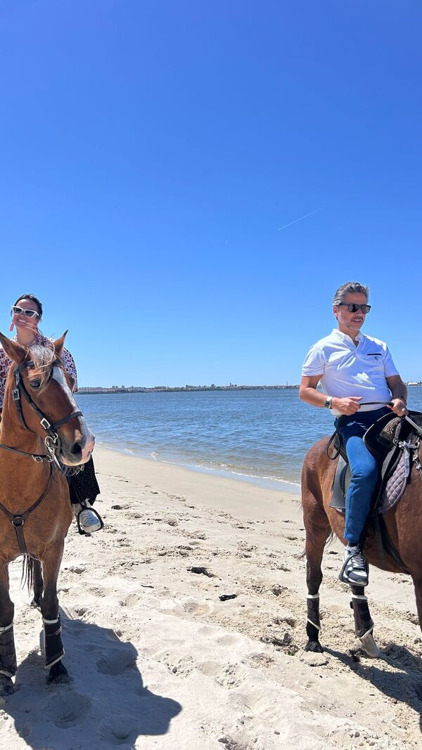 Um homem e uma mulher andam a cavalo na praia