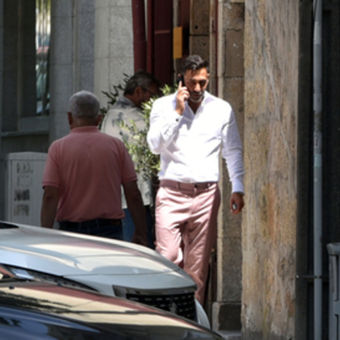 Homem ao telefone na rua com camisa branca e calças rosa
