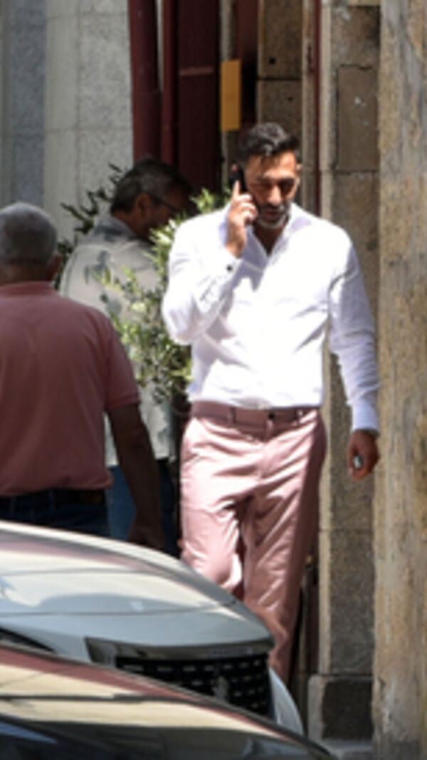 Homem ao telefone na rua com camisa branca e calças rosa