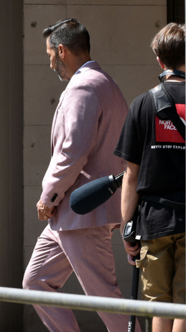 Homem de fato rosa caminha com equipa de filmagem