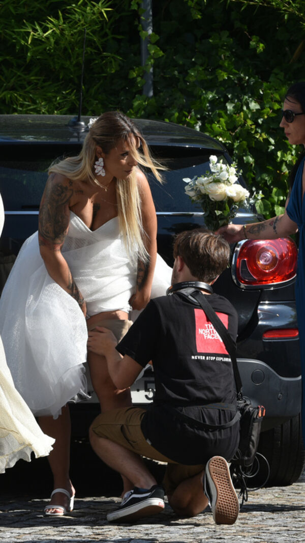 Fotógrafo ajuda noiva junto a convidados e carro em dia de casamento