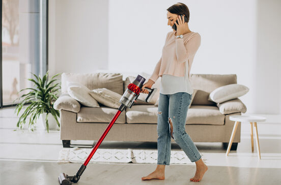 Mulher aspira a casa enquanto fala ao telemóvel