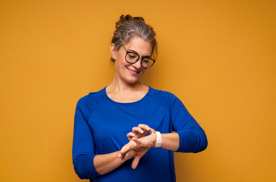 Mulher monitoriza a frequência cardíaca e passos no smartwatch.
