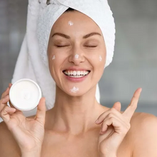 Mulher aplica creme no rosto após o banho