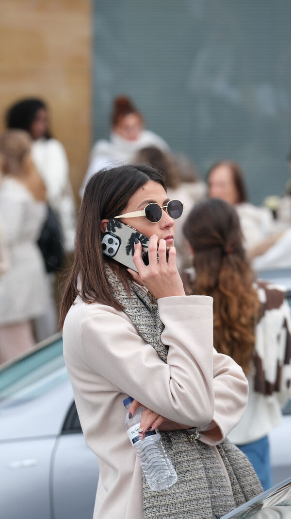 Mulher ao telefone com pessoas em segundo plano