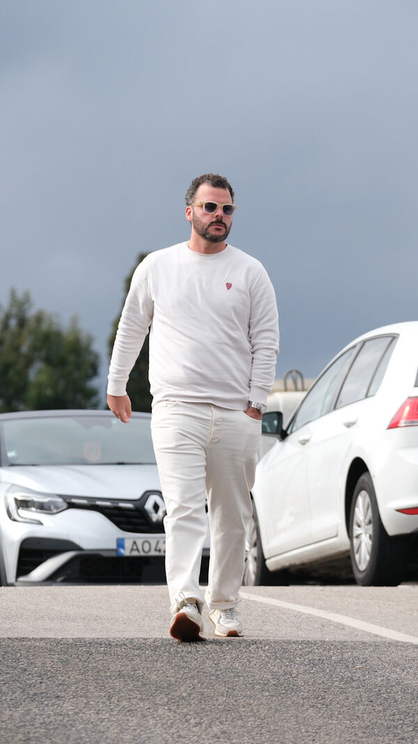 Homem caminha em estacionamento com carros ao fundo