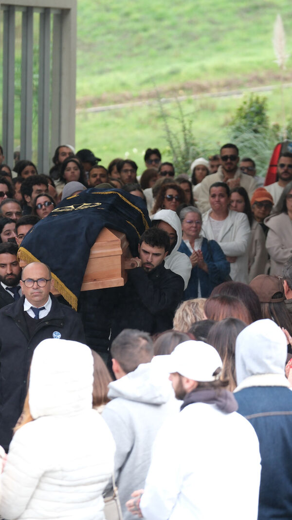 Funeral com caixão transportado por homens sob o olhar atento de populares