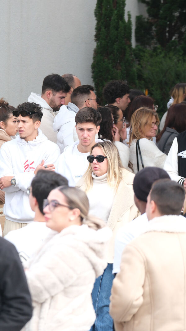 Pessoas reunidas num local, algumas com roupas claras e óculos de sol