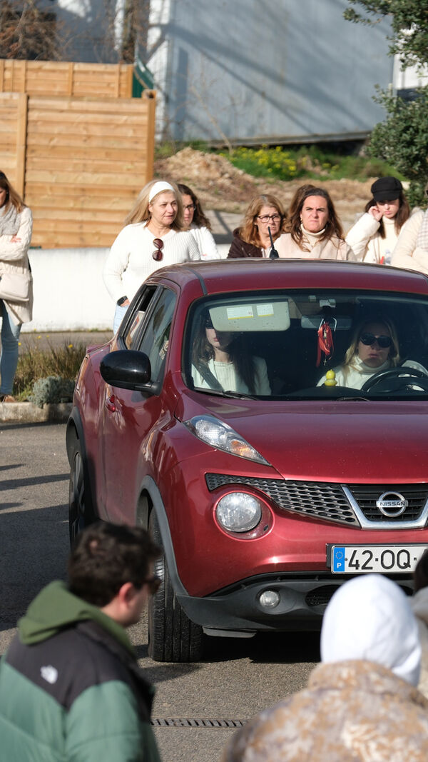 Pessoas juntas junto a um carro vermelho num dia ensolarado