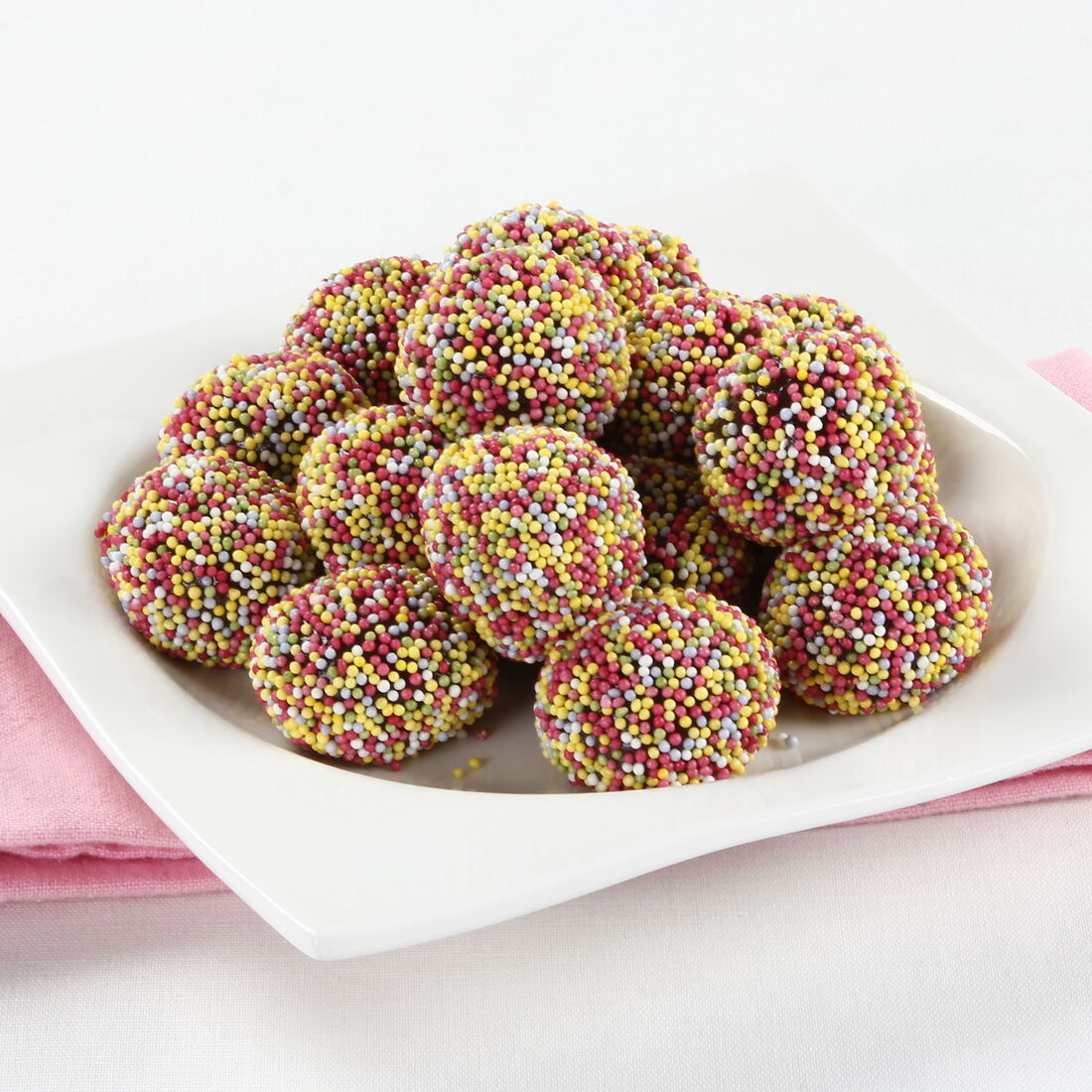 Doce colorido em prato branco com guardanapo rosa