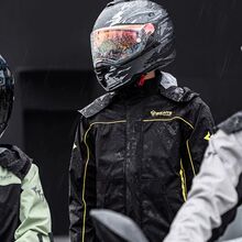 Motards enfrentam a chuva com equipamento impermeável para o inverno.
