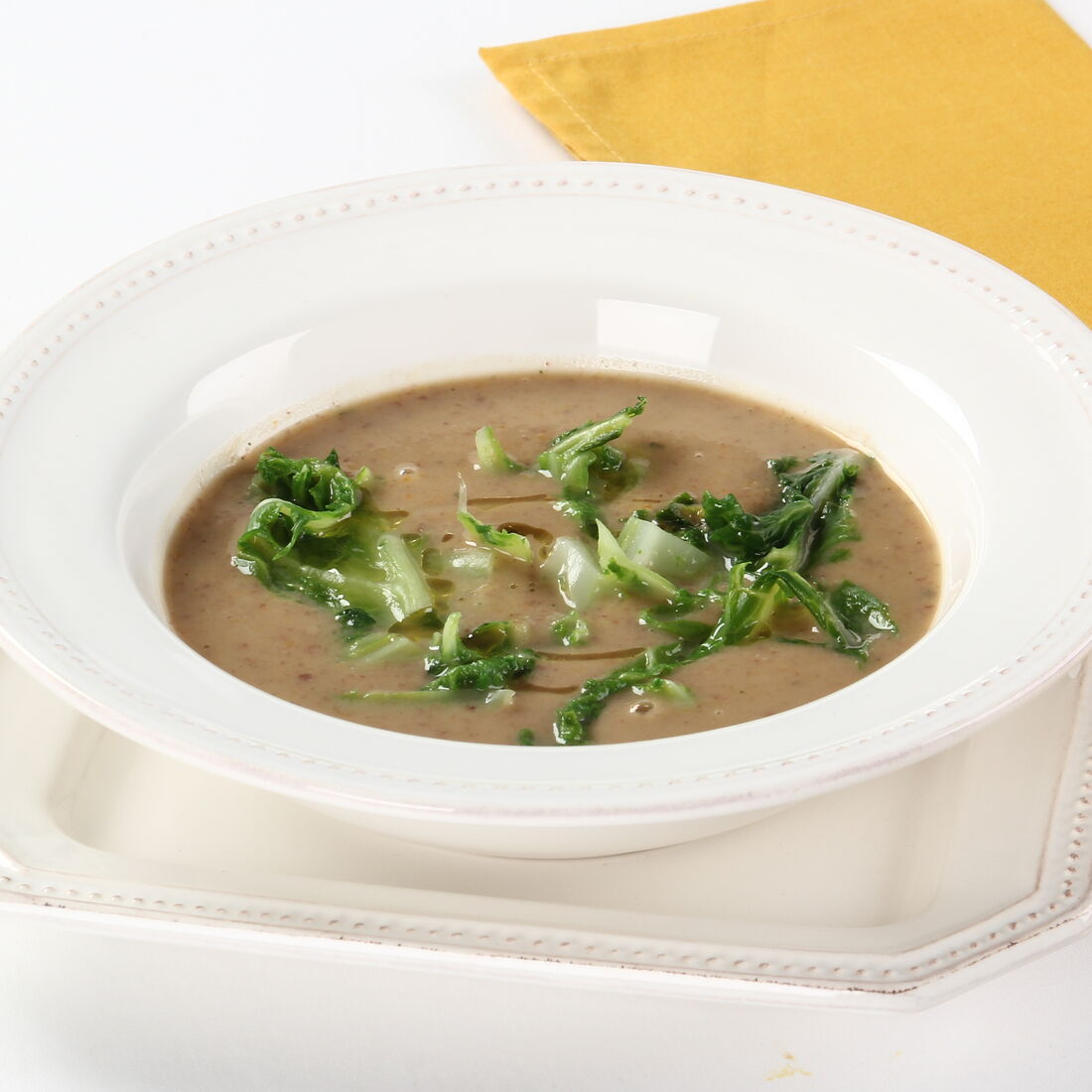 Sopa de feijão com couve num prato branco, pronta a servir