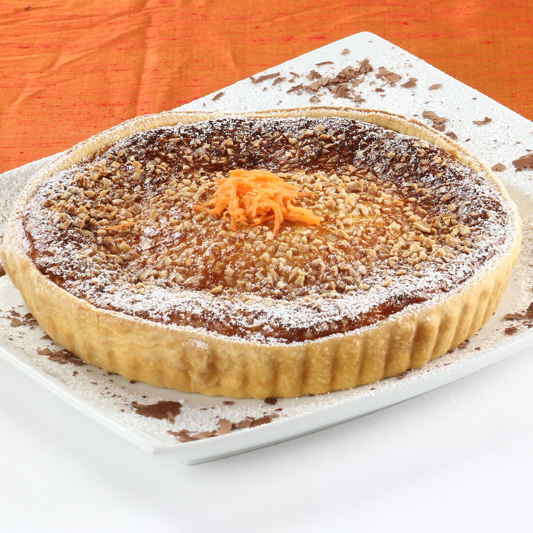 Tarte de amêndoa polvilhada com açúcar e decorada com raspas de laranja