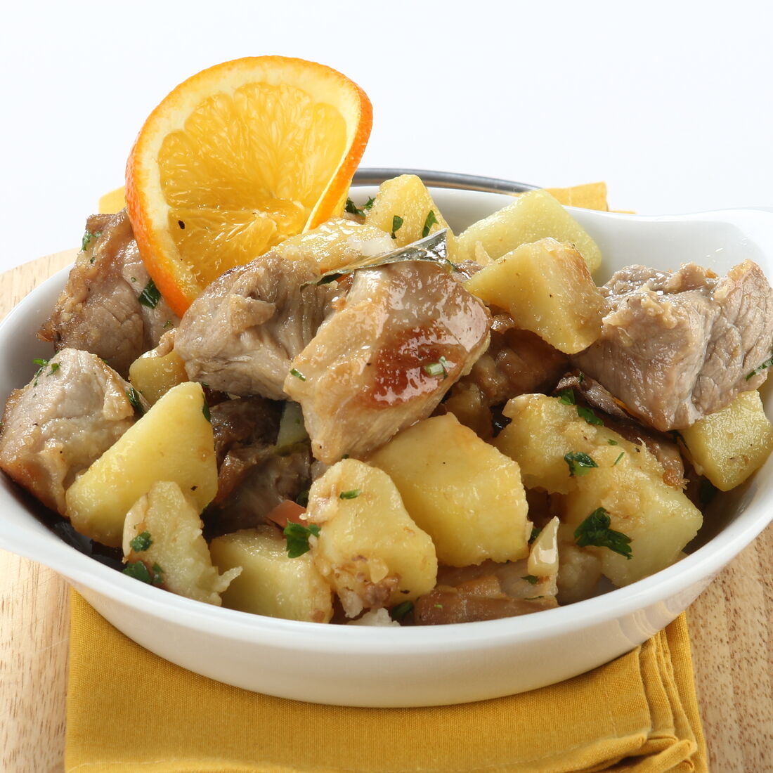 Prato de carne de porco com batatas e uma rodela de laranja como decoração