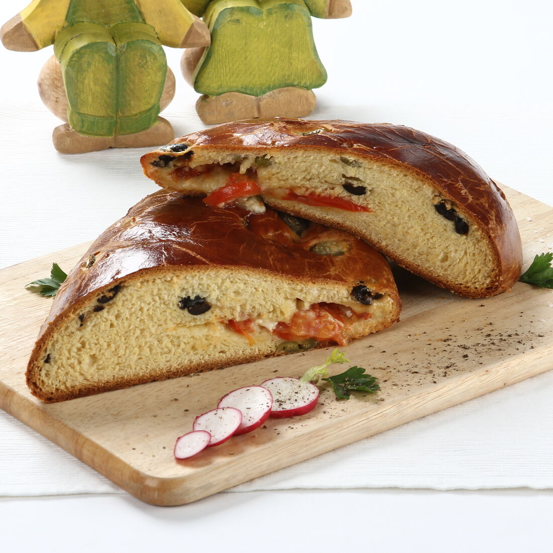 Folar de azeitonas recheado com tomate e queijo, cortado e servido numa tábua de madeira