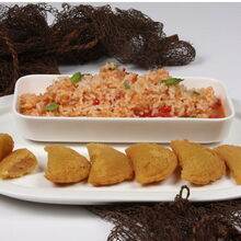 Rissóis de peixe dourados acompanham arroz de tomate, numa apresentação tradicional