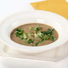 Sopa de feijão com couve num prato branco, pronta a servir