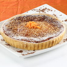 Tarte de amêndoa polvilhada com açúcar e decorada com raspas de laranja