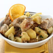 Prato de carne de porco com batatas e uma rodela de laranja como decoração