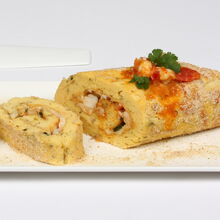 Torta de camarão com molho e ervas numa travessa branca