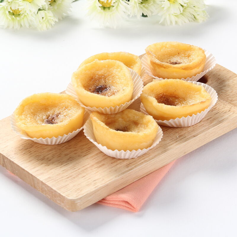 Queijadinhas de leite, dispostas com flores brancas, para uma mesa elegante