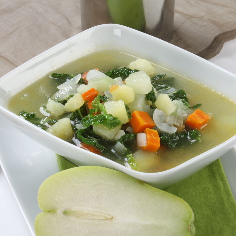 Sopa de lombardo e chuchu numa tigela quadrada, com meio chuchu ao lado