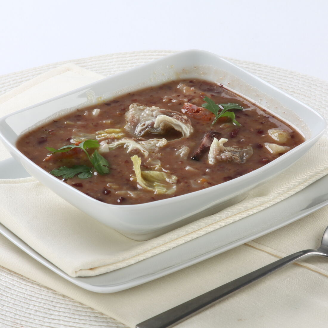 Sopa da Pedra num recipiente branco, com colher ao lado