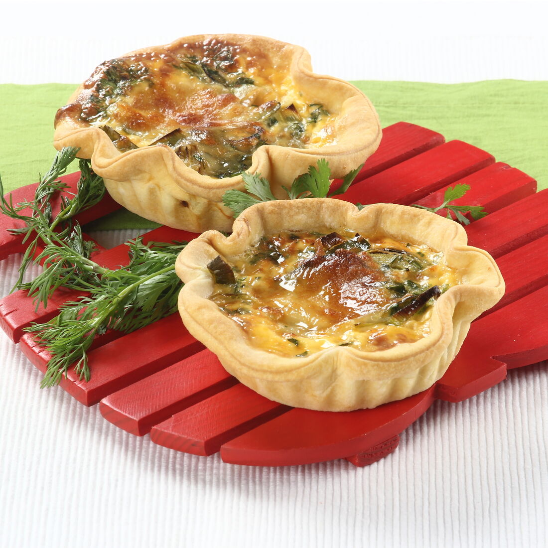 Tarteletes de alho-francês prontas para servir numa tábua de madeira