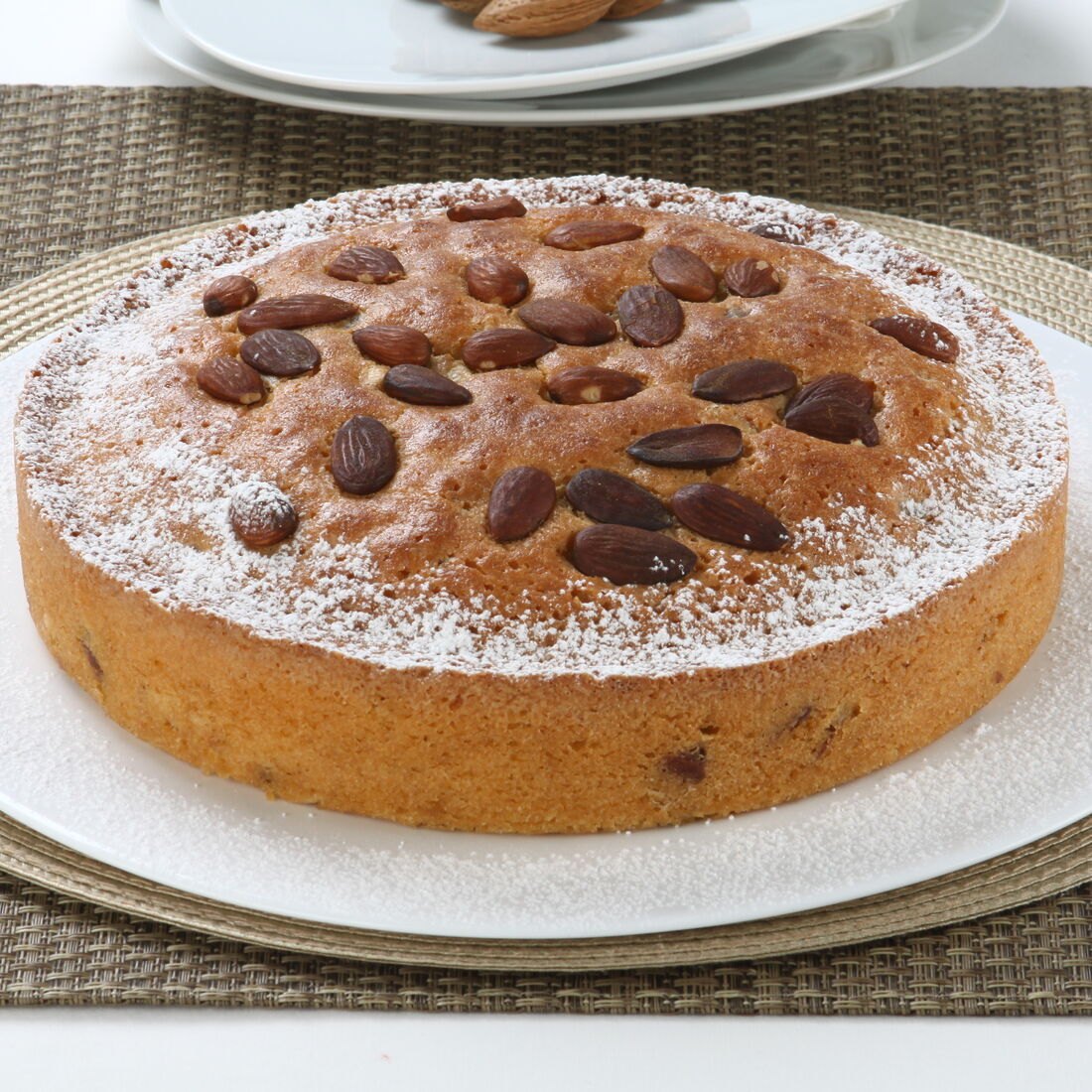 Bolo de amêndoa polvilhado com açúcar e decorado com amêndoas inteiras