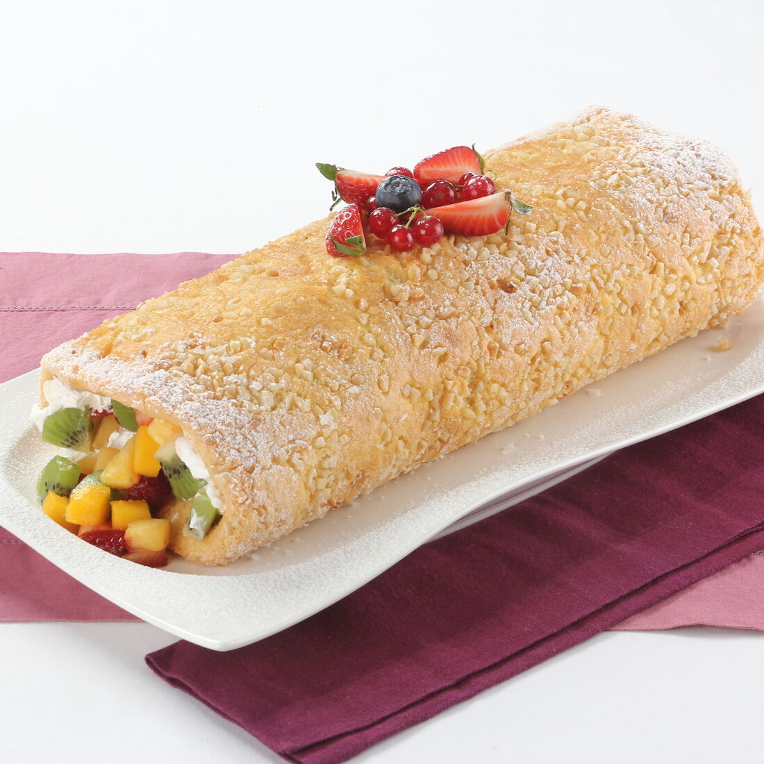 Torta de amêndoa recheada com salada de fruta fresca e decorada com frutos vermelhos