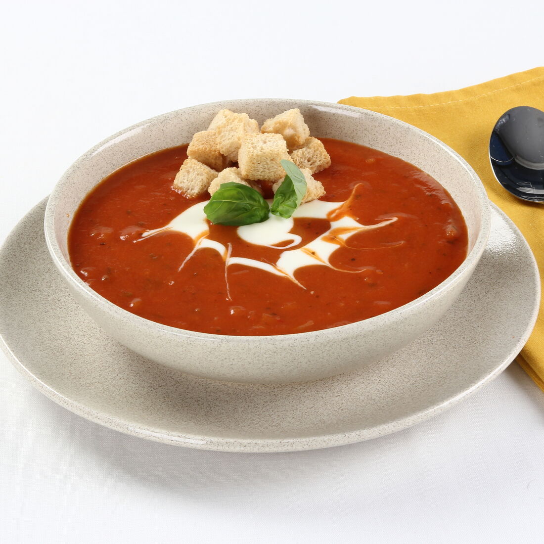 Sopa de tomate cremosa com cubos de pão e manjericão para um toque de frescura