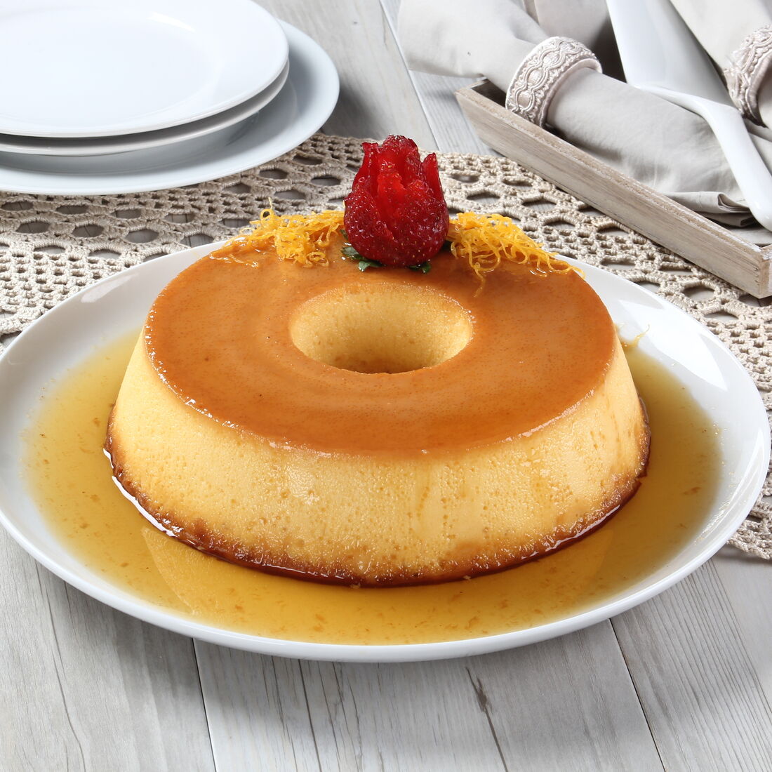 Pudim flã com morango e fios de ovos, sobre mesa de madeira