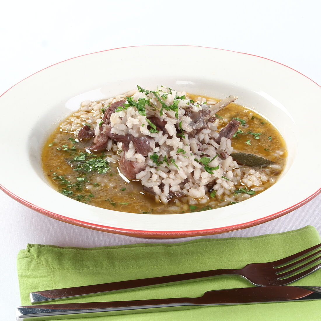 Prato de arroz de coelho com garfo e faca sobre um guardanapo