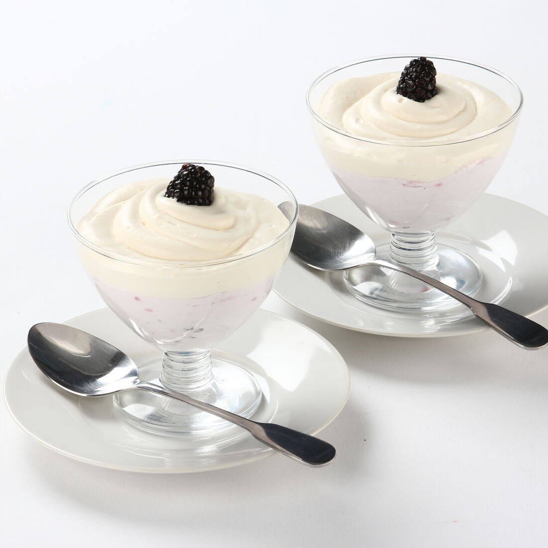 Mousse bicolor com natas e amoras pretas em taças de vidro