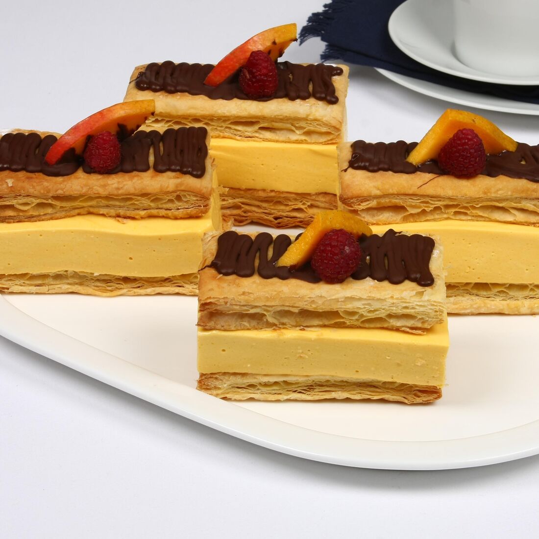 Fatias de massa folhada com creme de manga e decoração de chocolate e framboesa