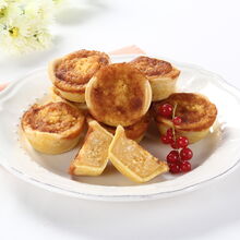 Queijadas de requeijão em prato branco com flores e um pano