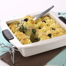 Bacalhau com espinafres gratinado, servido numa travessa branca com azeitonas pretas