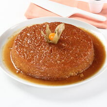 Arroz-doce enformado, decorado com fisális, em travessa branca com molho