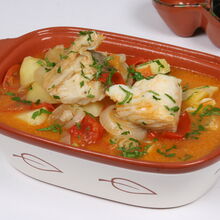 Bacalhau guisado com batatas, tomate e cebola num recipiente de barro