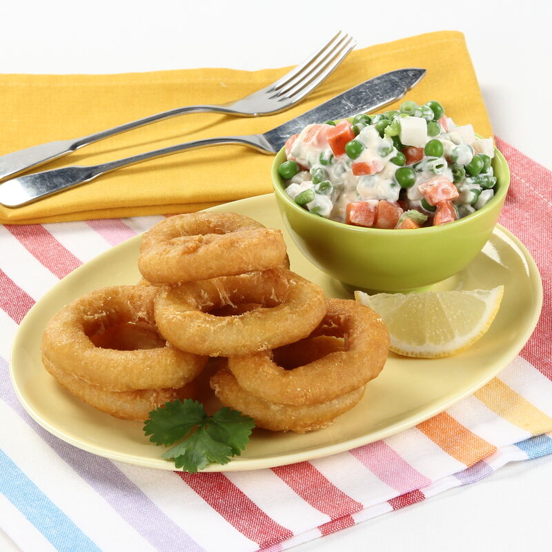 Calamares com salada russa, limão e talheres sobre panos coloridos