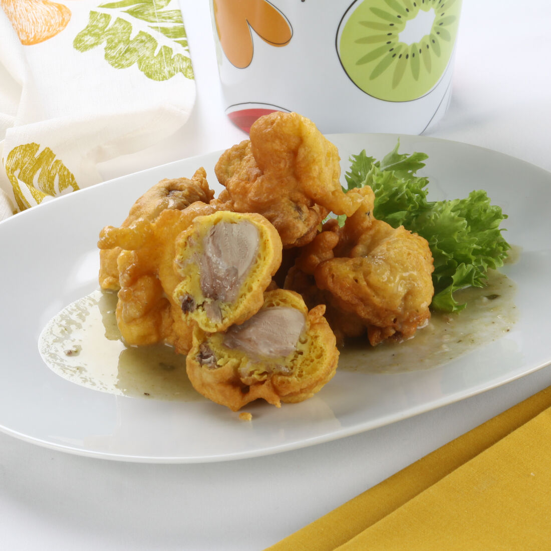 Frango frito servido num prato branco com alface e um guardanapo amarelo