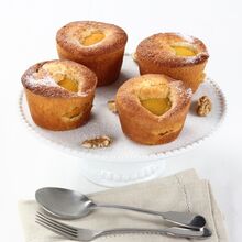 Bolos de pêssego apetitosos em suporte branco, com talheres e guardanapo