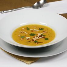 Creme de abóbora com amêndoas num prato branco, pronto para servir